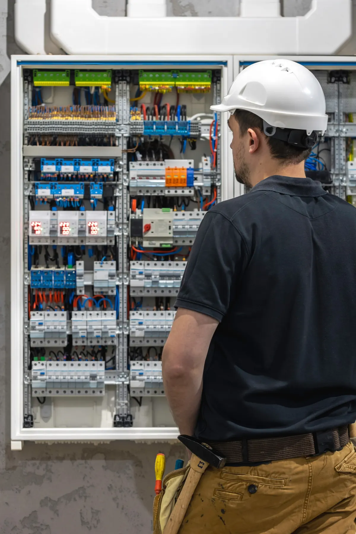 Technicien devant un tableau électrique tertiaire