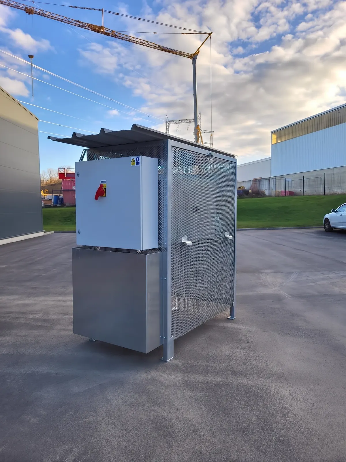Shelter grillagé avec coffret électrique sur un site industriel